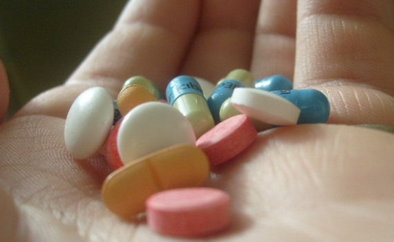 hand holding different tablets and capsules