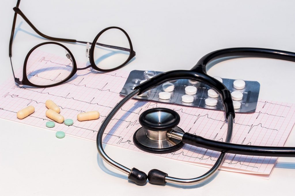 glasses on table with tablets and stethoscope